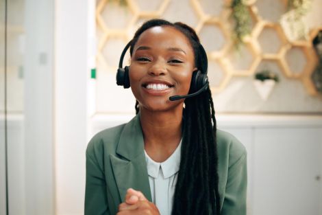 smiling woman wearing phone headset for customer service at front desk reception